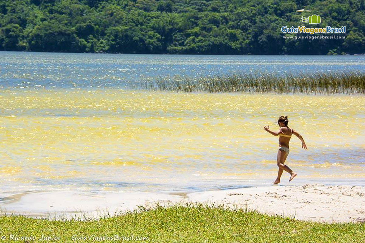 Imagem de uma menina entrando correndo na Lagoa Peri.
