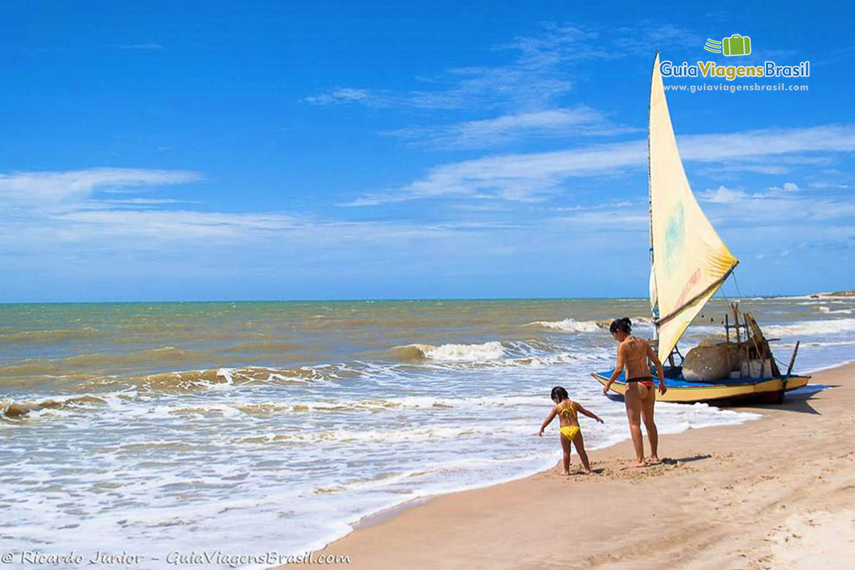 Imagem de mãe e filha na beira do mar na Praia Canoa Quebrada. 