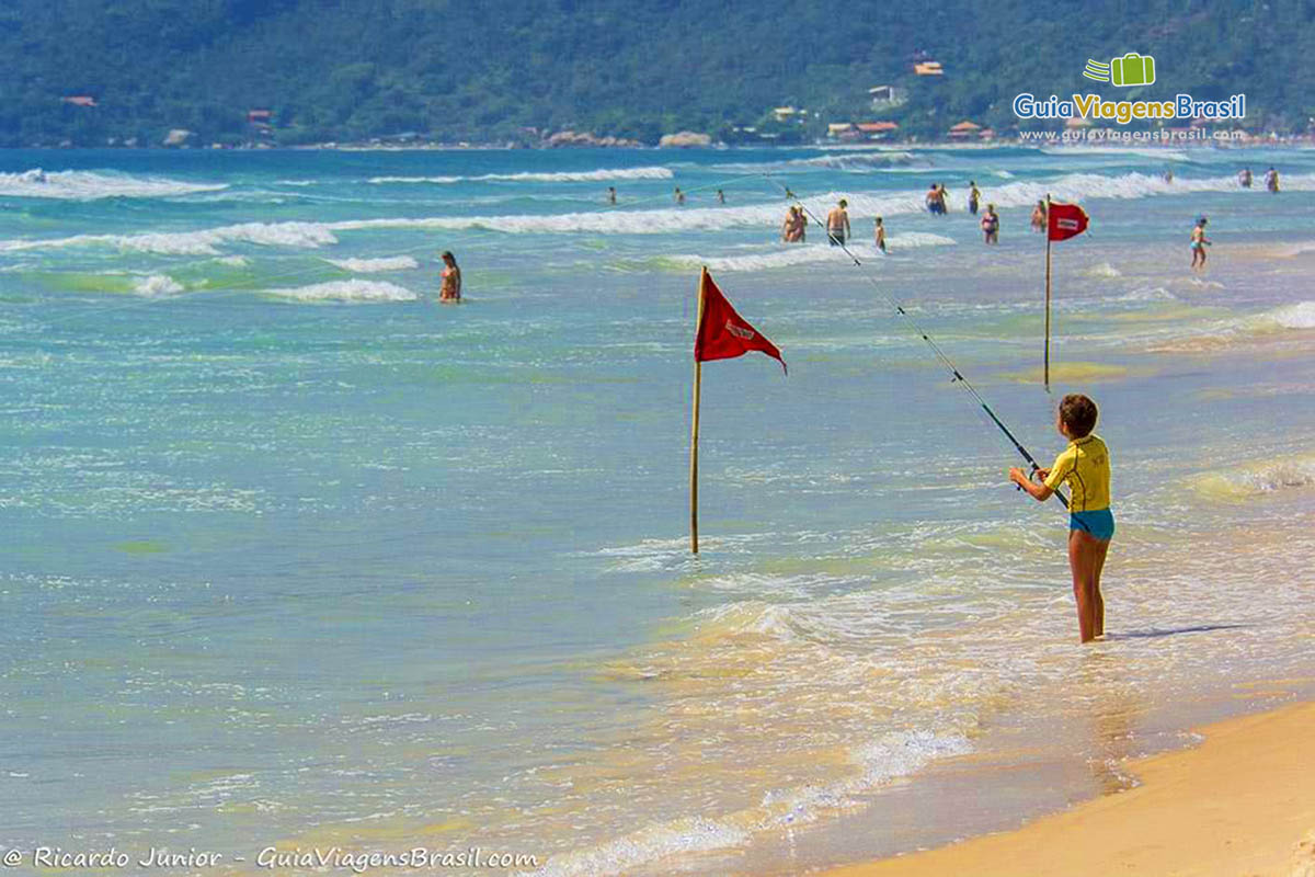 Imagem de um menino pescando no mar.