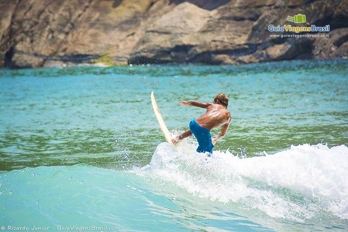 Imagem de um menino subindo na prancha, em Ilhabela.