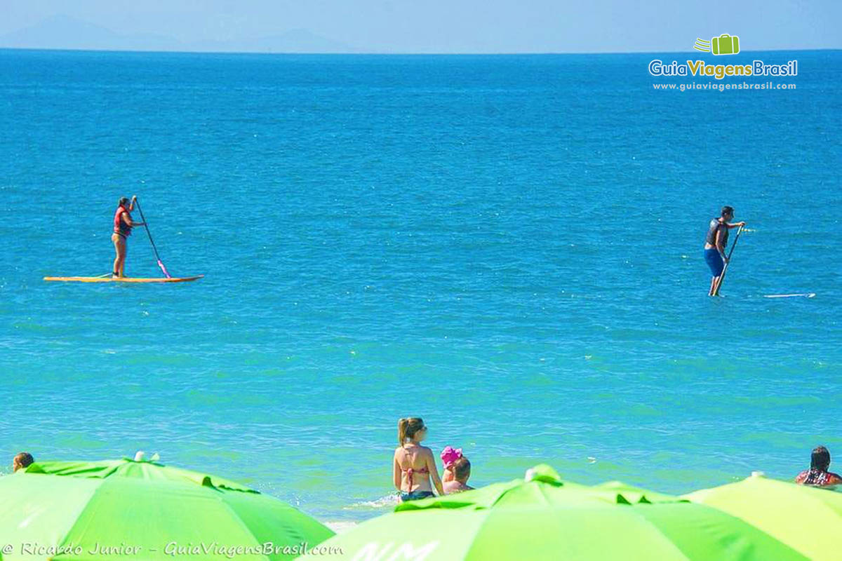 Imagem duas pessoas praticando stand up paddle na Praia Bombinhas.