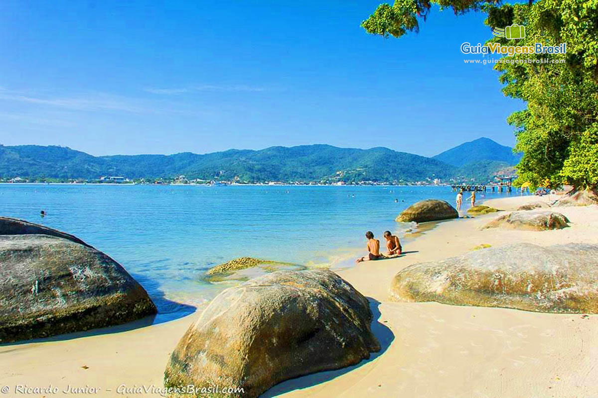 Imagem de crianças brincando na areia da praia da ilha.