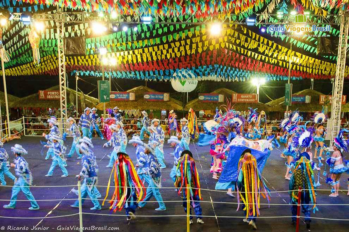 Imagem do palco com um grupo dançando e a decoração de bandeiras.