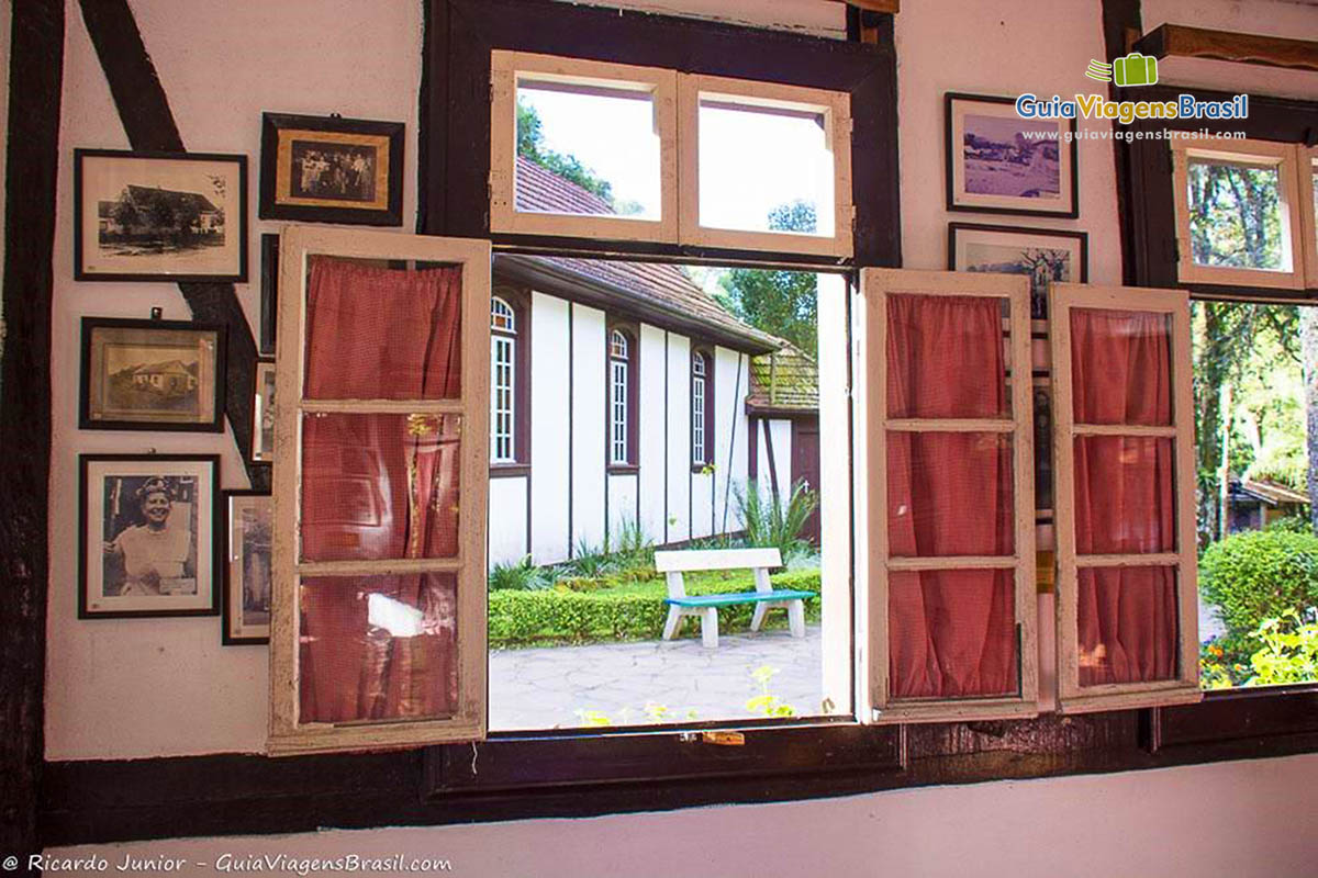 Imagem de uma janela aberta com quadros na parede.