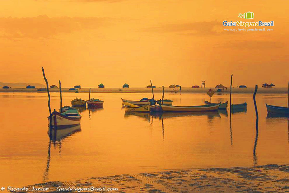 Imagem de belo entardecer com barcos no mar.