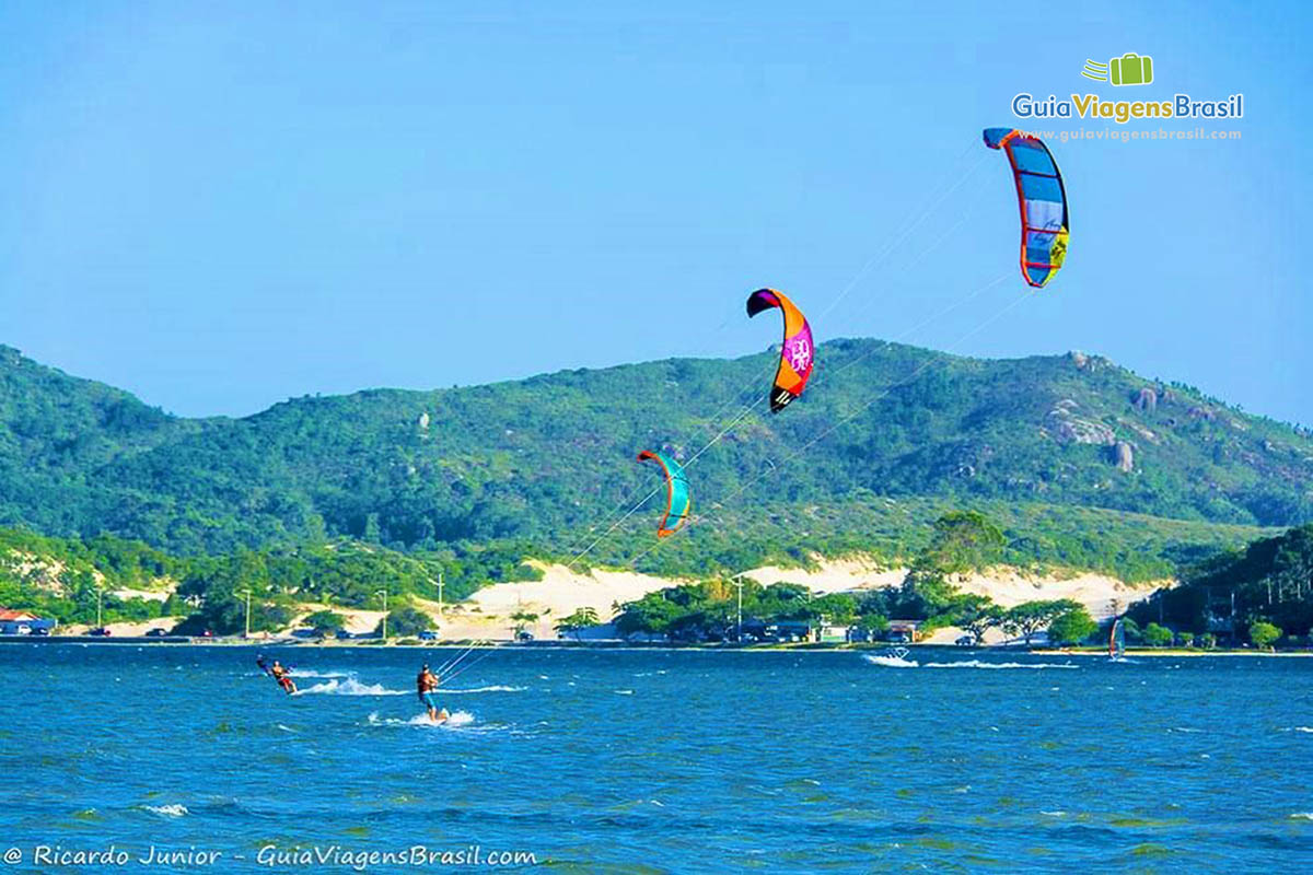 Imagem de pessoas praticando kitesurf.