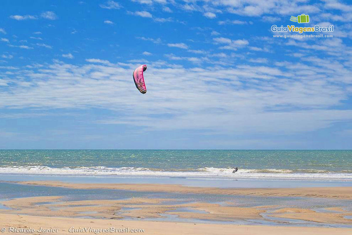 Imagem de prática de kitesurf na praia. 