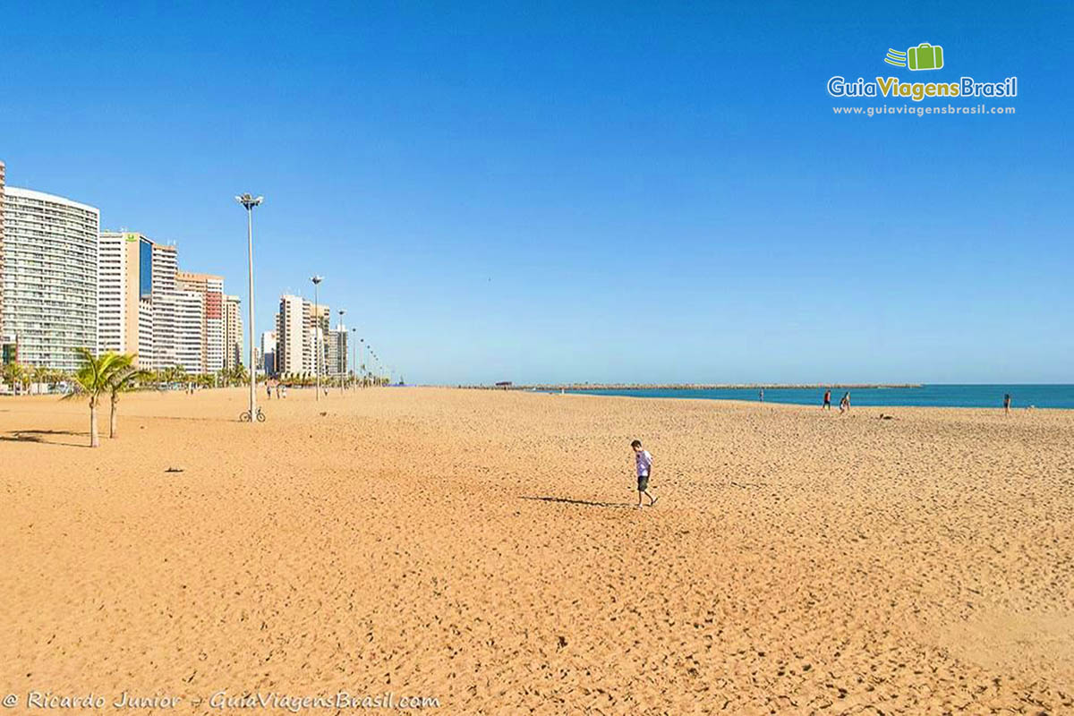 Imagem da grande faixa de areia da praia em Fortaleza.