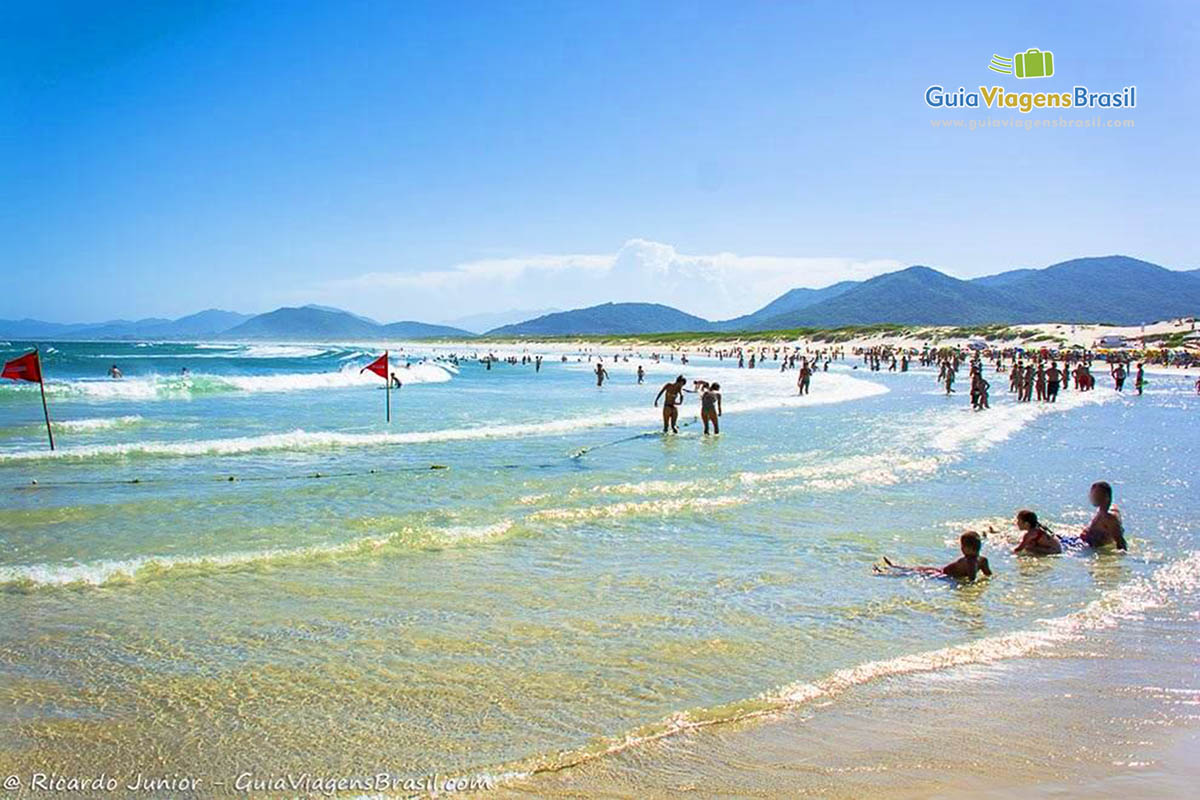 Imagem das pessoas nas águas da praia.