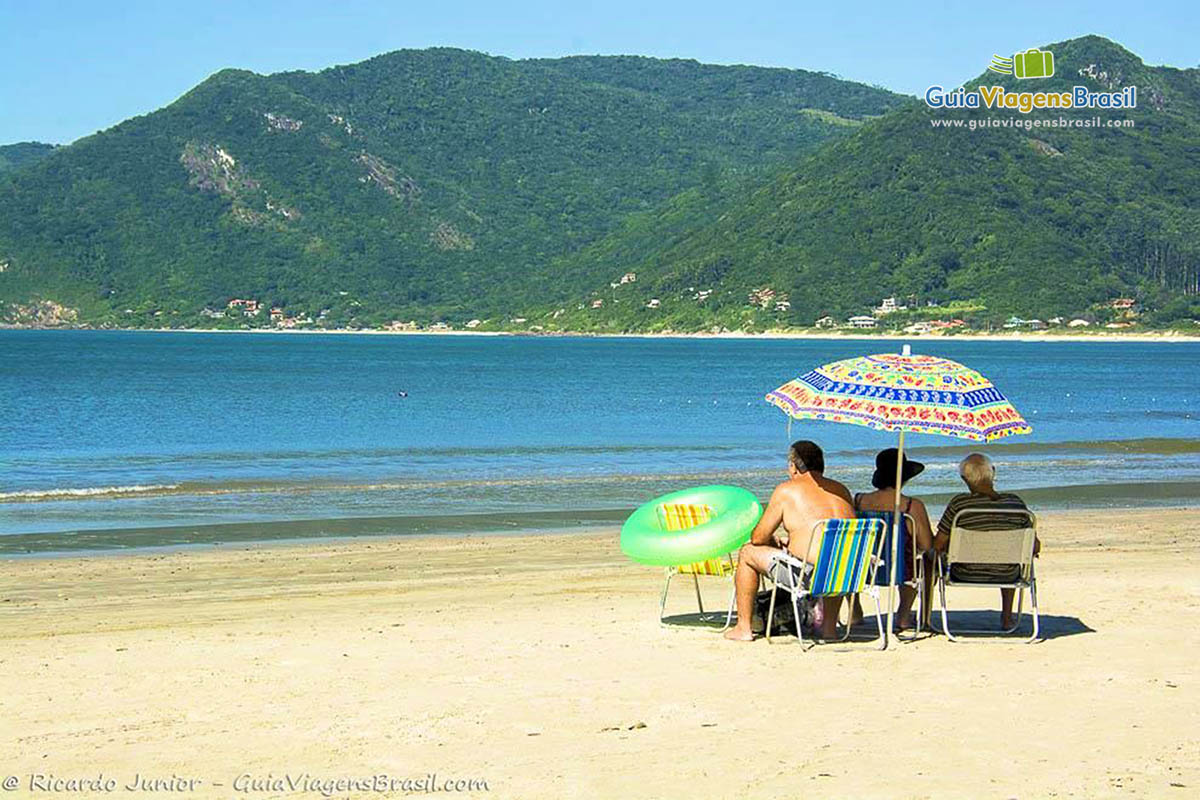 Imagem de família embaixo de seu guarda sol aproveitando a tarde na Praia Pantano Sul.