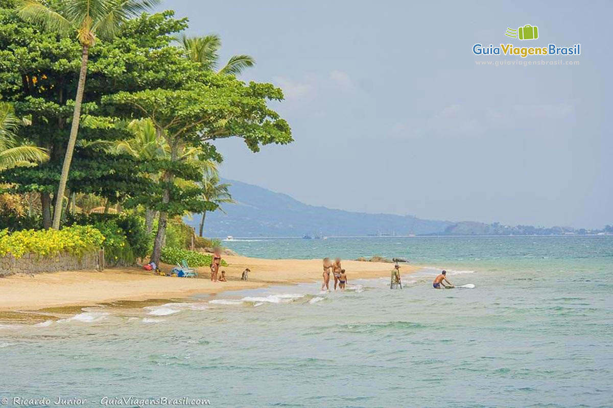 Imagem de uma família no mar calmo da Praia do Sino.