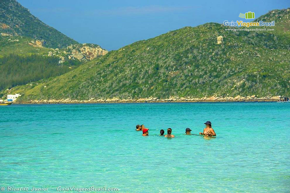 Imagem de uma família no mar se deliciando nas águas trasnlúcidas da praia.