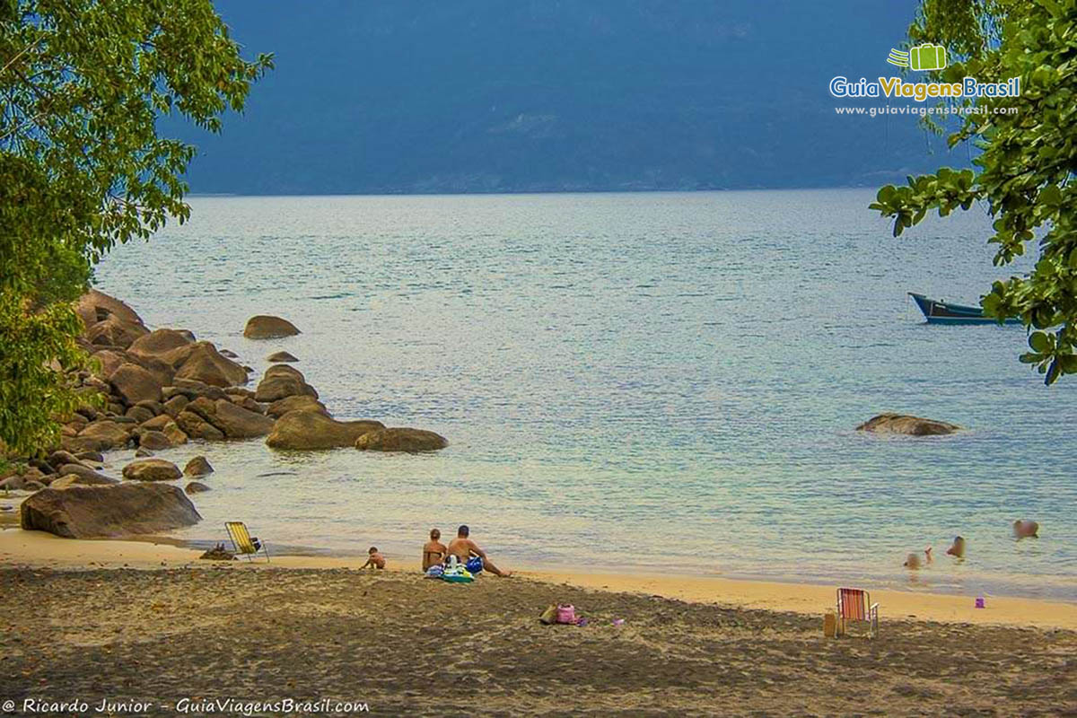 Imagem de família curtindo as águas da Praia do Veloso. 