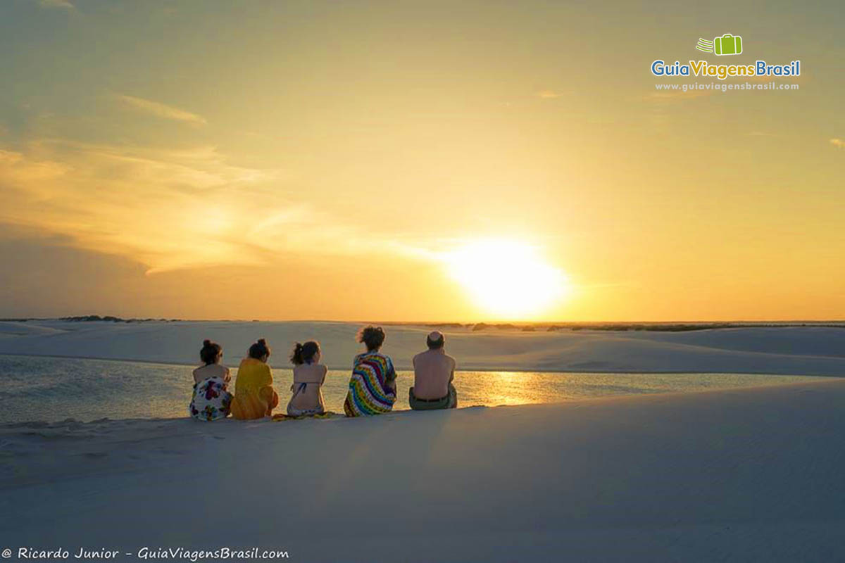 Imagem de família sentados nas dunas admirando o lindo fenômeno da natureza.