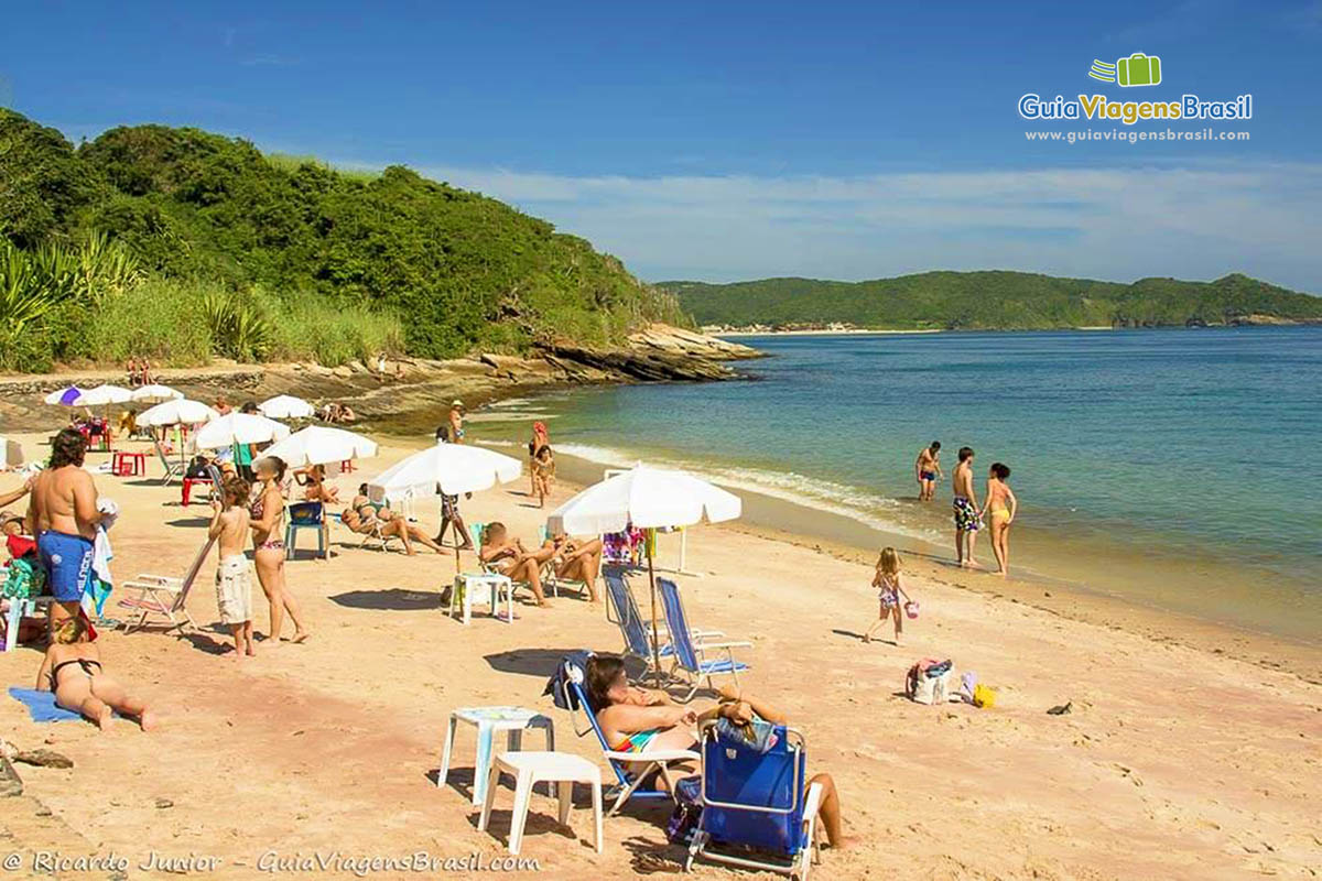 Imagem de familias nas areias e no mar, aproveitando o belo dia.