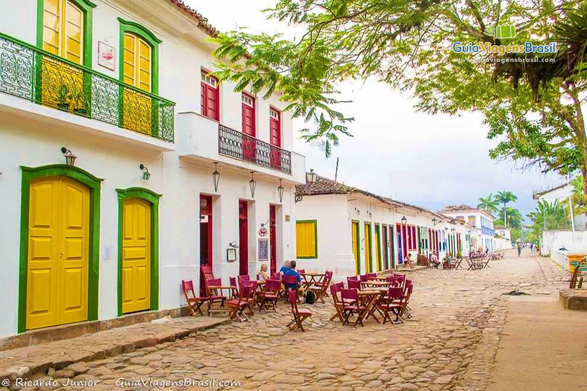 Imagem de barzinho com mesas na rua para alegrar turistas.