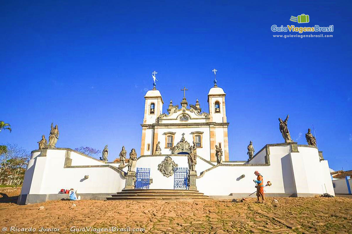 Imagem de gari limpando em volta dos muros da basílica.