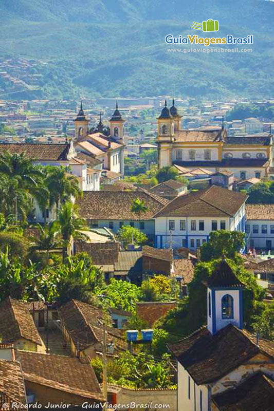 Imagem de igrejas e casarões e ao fundo a linda paisagem da serra.