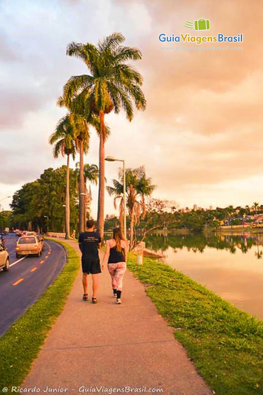 Imagem de casal caminhando em volta ao lago.