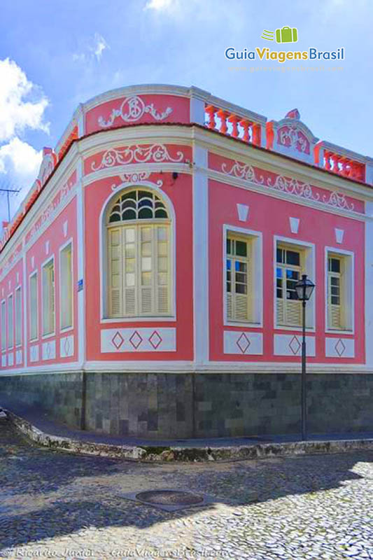 Imagem da casa rosa de esquina, detalhes de molduras das janelas e portas.