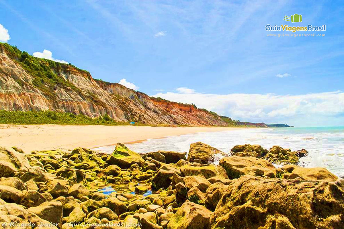 Imagem de pequenas rochas e ao fundo a praia do Club Med.