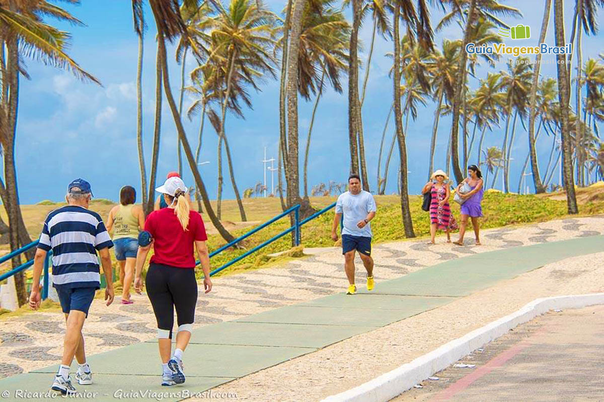 Imagem de pessoas caminhando no calçadão da Praia de Jardim de Alah, em Salvador.