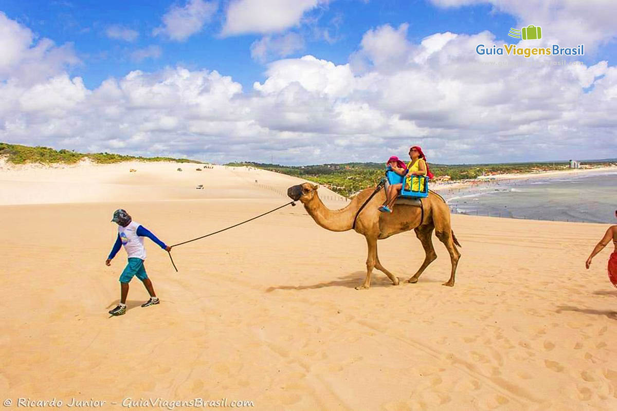 Imagem de turistas no dromedário e a bela paisagem de Genipabu