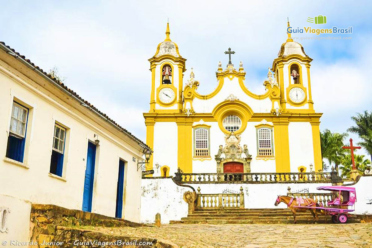 Imagem de uma charrete rosa em frente a Igreja de Santo Antônio.