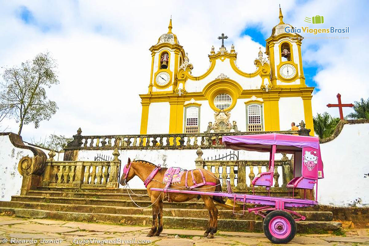 Imagem aproximada da charrete e da igreja, em Tiradentes.