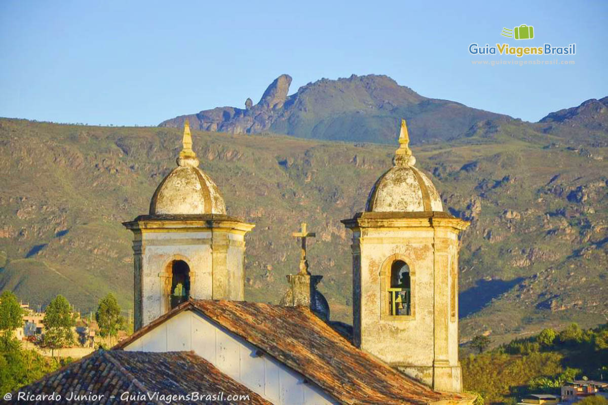 Imagem dos sinos da igreja e ao fundo o Pico do Itacolomi.