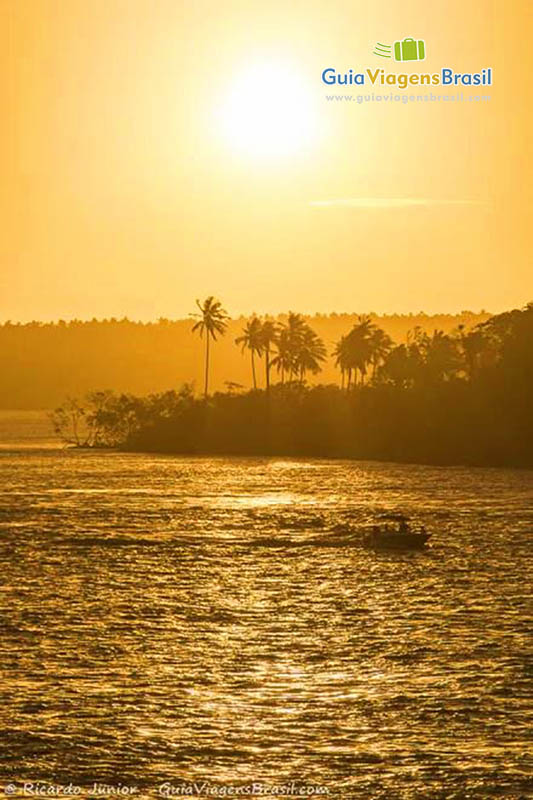Imagem de barco nas águas da lagoa com luz do sol maravilhosa.