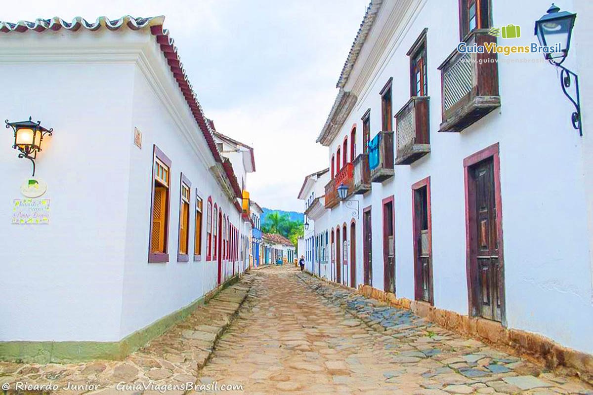 Imagem de luminária das casas antigas acessas e rua estreita de paralelepípedo.