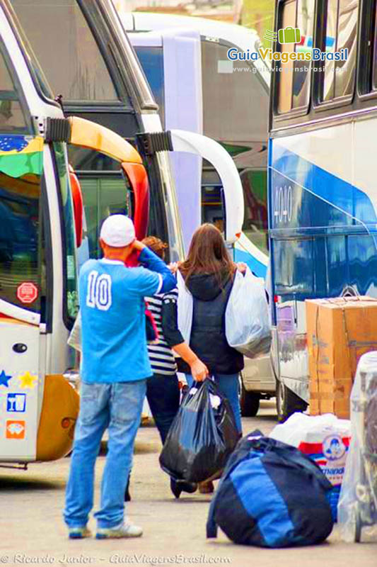 Imagem de duas pessoas perto do ônibus com suas compras da 25 de março.