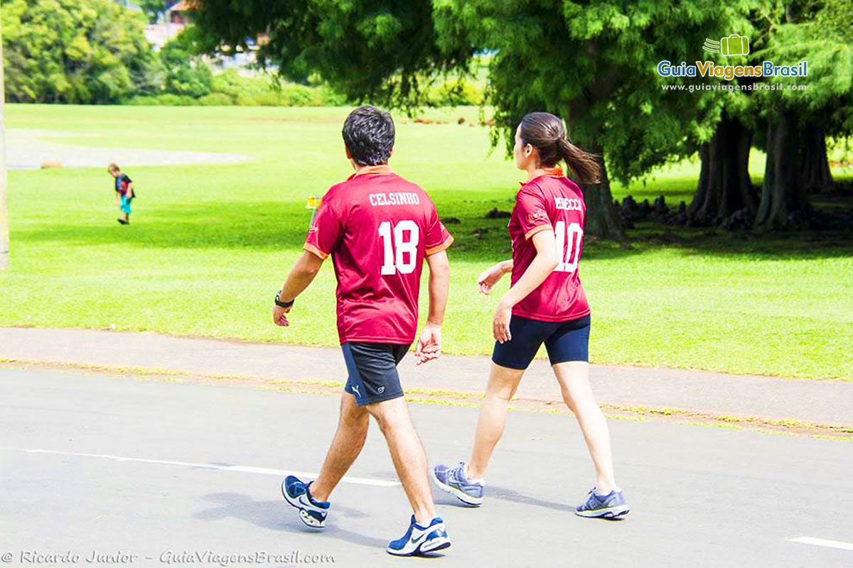 Imagem de casal caminhando em meio ao verde do Parque Birigui, em Curitiba.