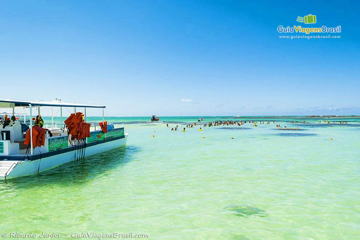 Imagem de barco e turistas aproveitando a piscina natural de Maragogi.