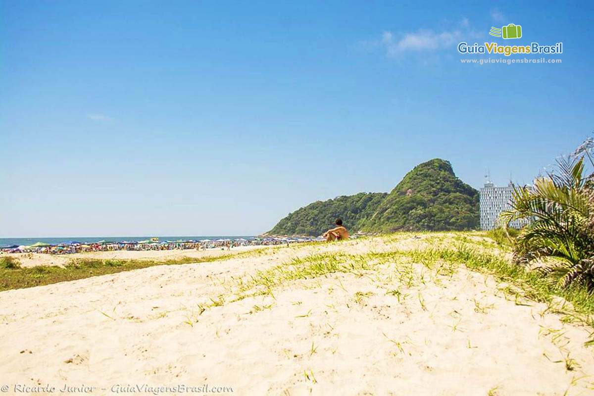 Imagem da areia clara com umas graminhas e ao fundo a Praia Brava, em Caiobá, Santa Catarina, Brasil.