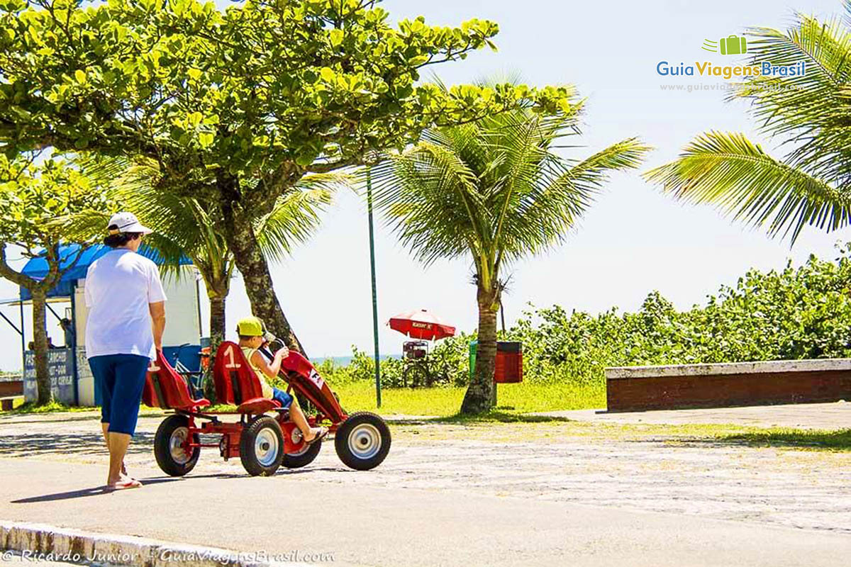 Imagem de um menino andando de carrinho na orla da Praia Brava, em Caiobá, Santa Catarina, Brasil.