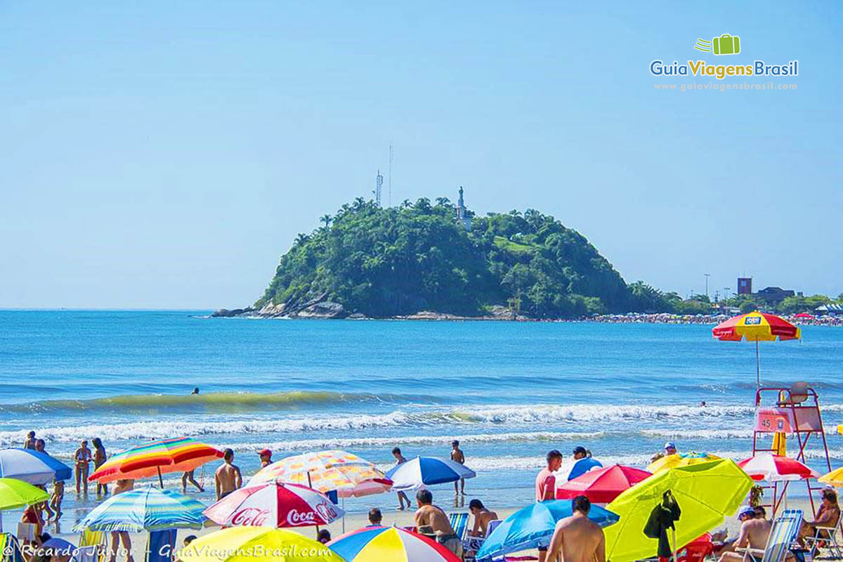 Imagem de vários guarda-sol coloridos alegrando a bela paisagem da Praia Central de Guaratuba, em Santa Catarina, Brasil.