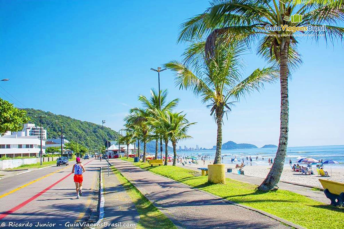 Imagem de turistas correndo na orla da praia, tendo de visão e linda Praia de Guaratuba, Santa Catarina, Brasil.