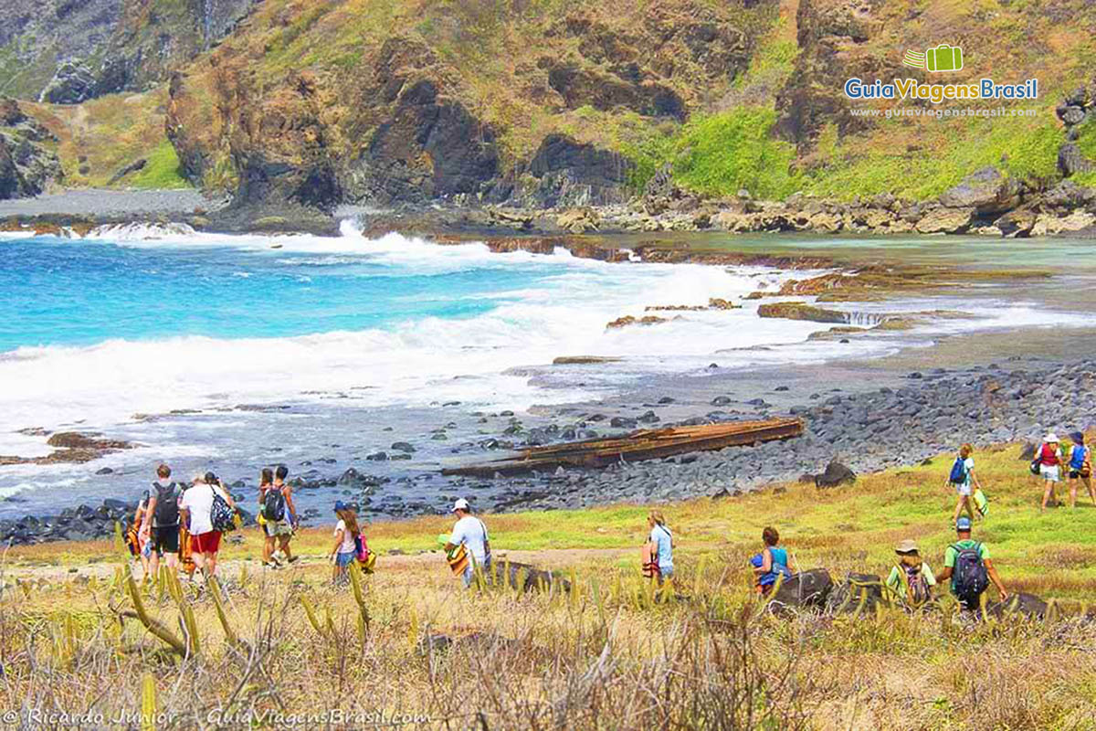 Imagem de turistas no fim da trilha na Praia da Atalaia, em Fernando de Noronha, Pernambuco, Brasil.