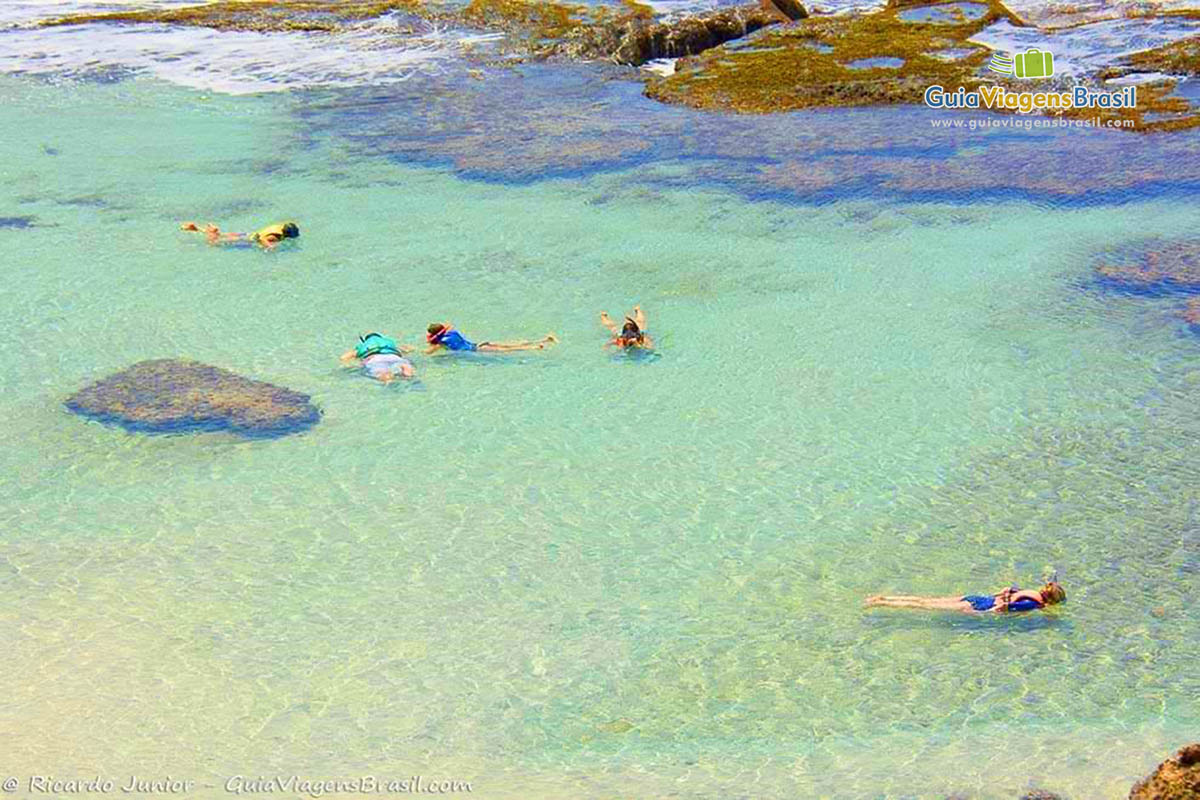 Imagem da piscina natural com águas translúcidas, turistas se esbaldando de tanta beleza natural, na Praia da Atalaia, em Fernando de Noronha, Pernambuco, Brasil.