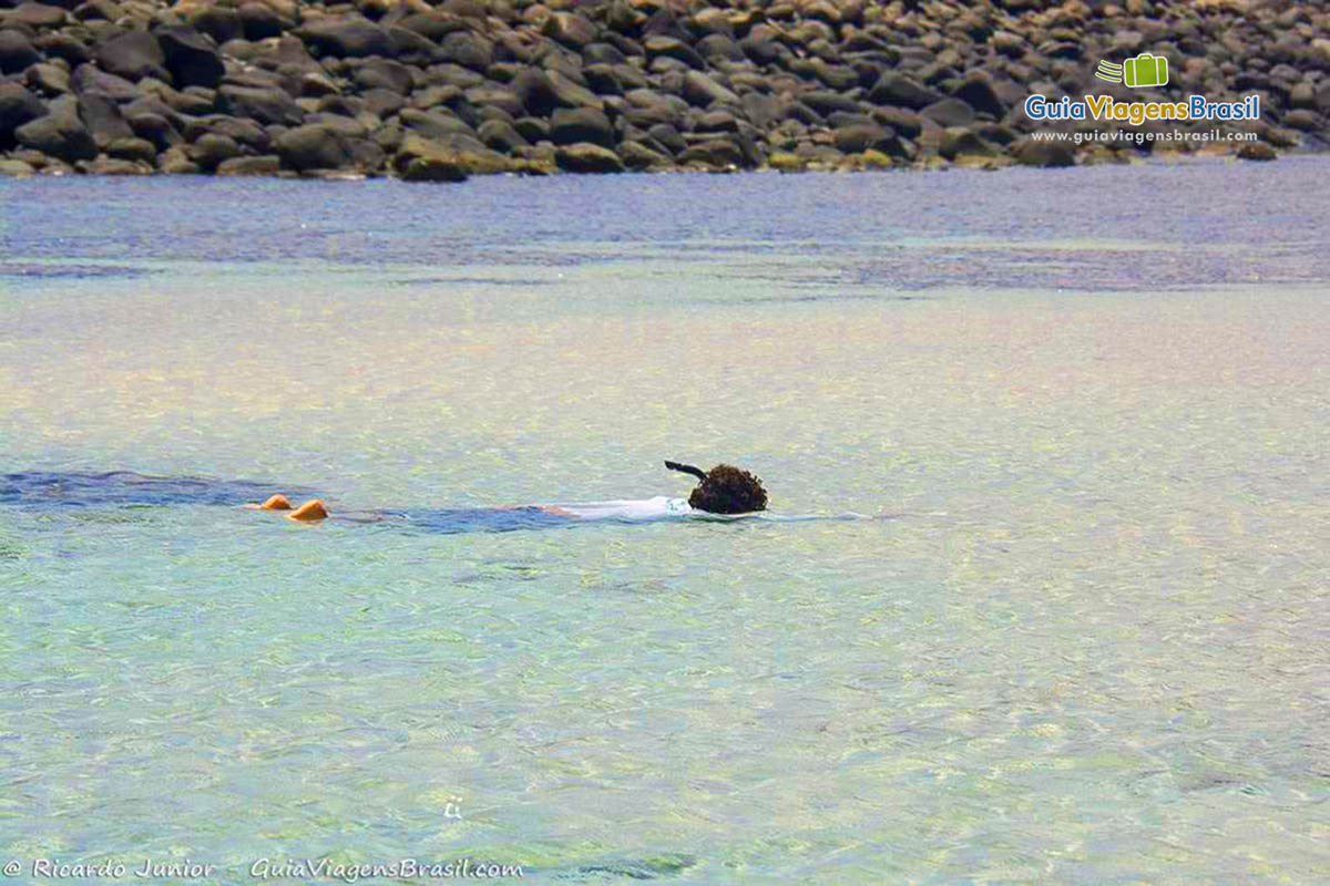 Imagem das calma piscina natural e criança mergulhando, pois trata-se de um excelente local para prática do mergulho, na Praia da Atalaia, em Fernando de Noronha, Pernambuco, Brasil.