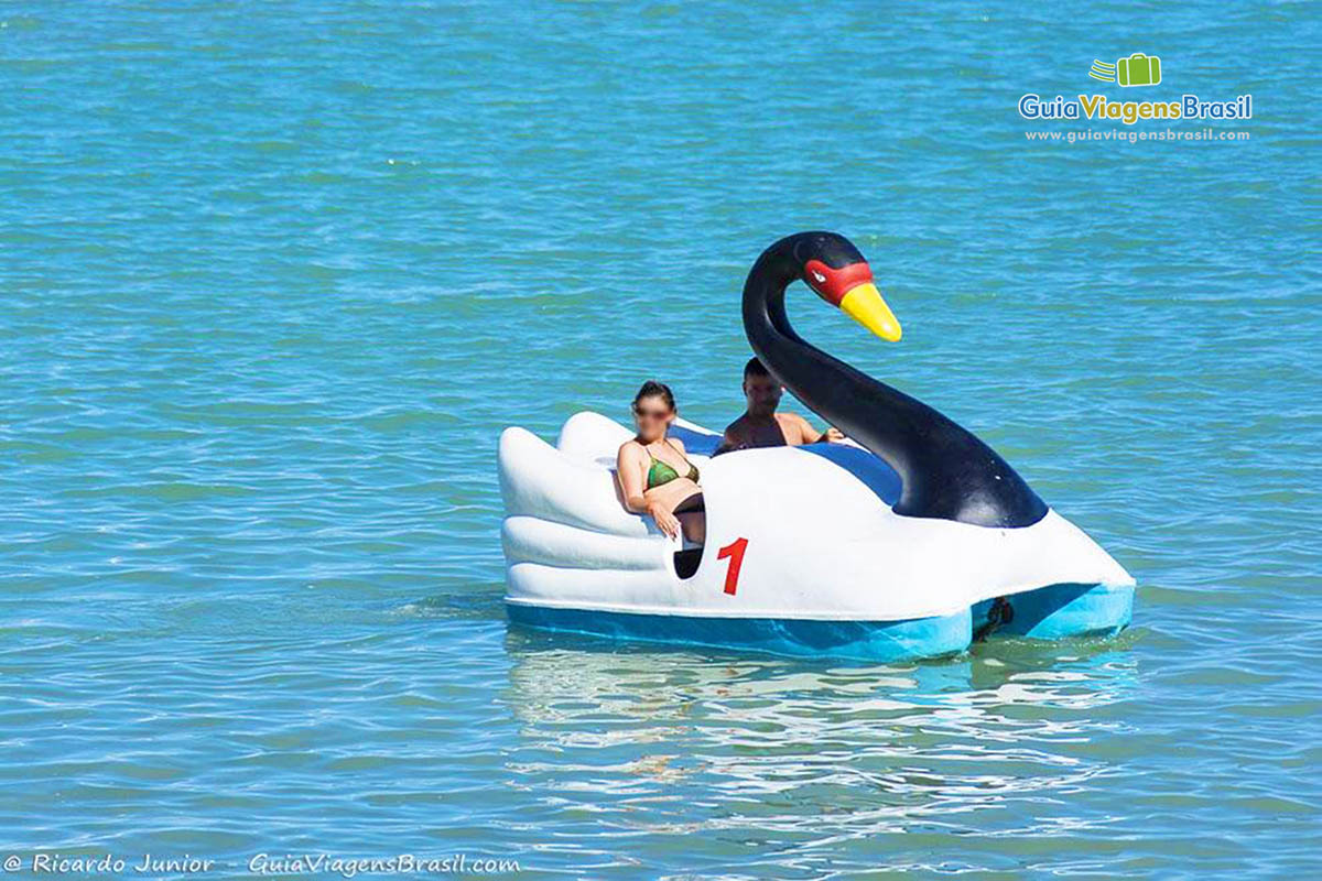 Imagem de turistas andando de pedalinho pelas águas cristalinas da Praia Barra de São Miguel, Alagoas, Brasil.