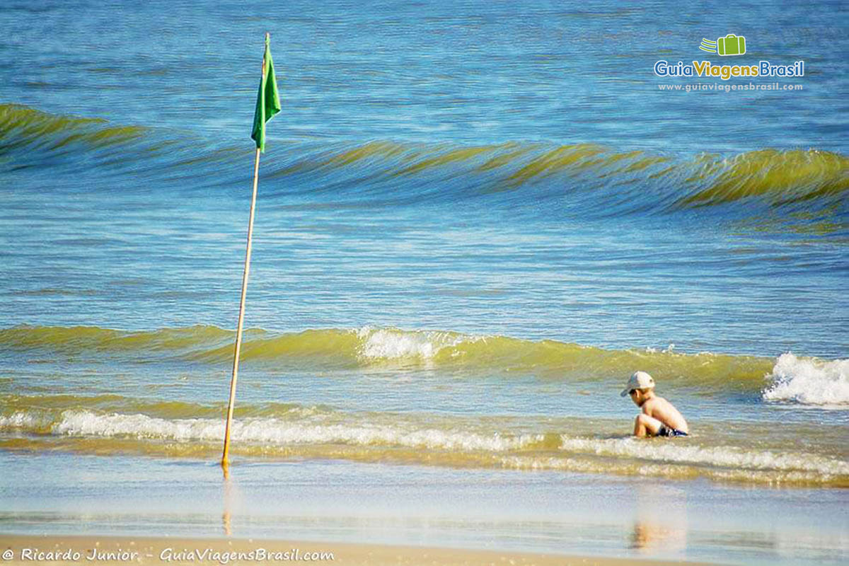 Imagem de um belo menino brincando nas águas da Praia Barra do Sai, em Itapoá, Santa Catarina, Brasil.
