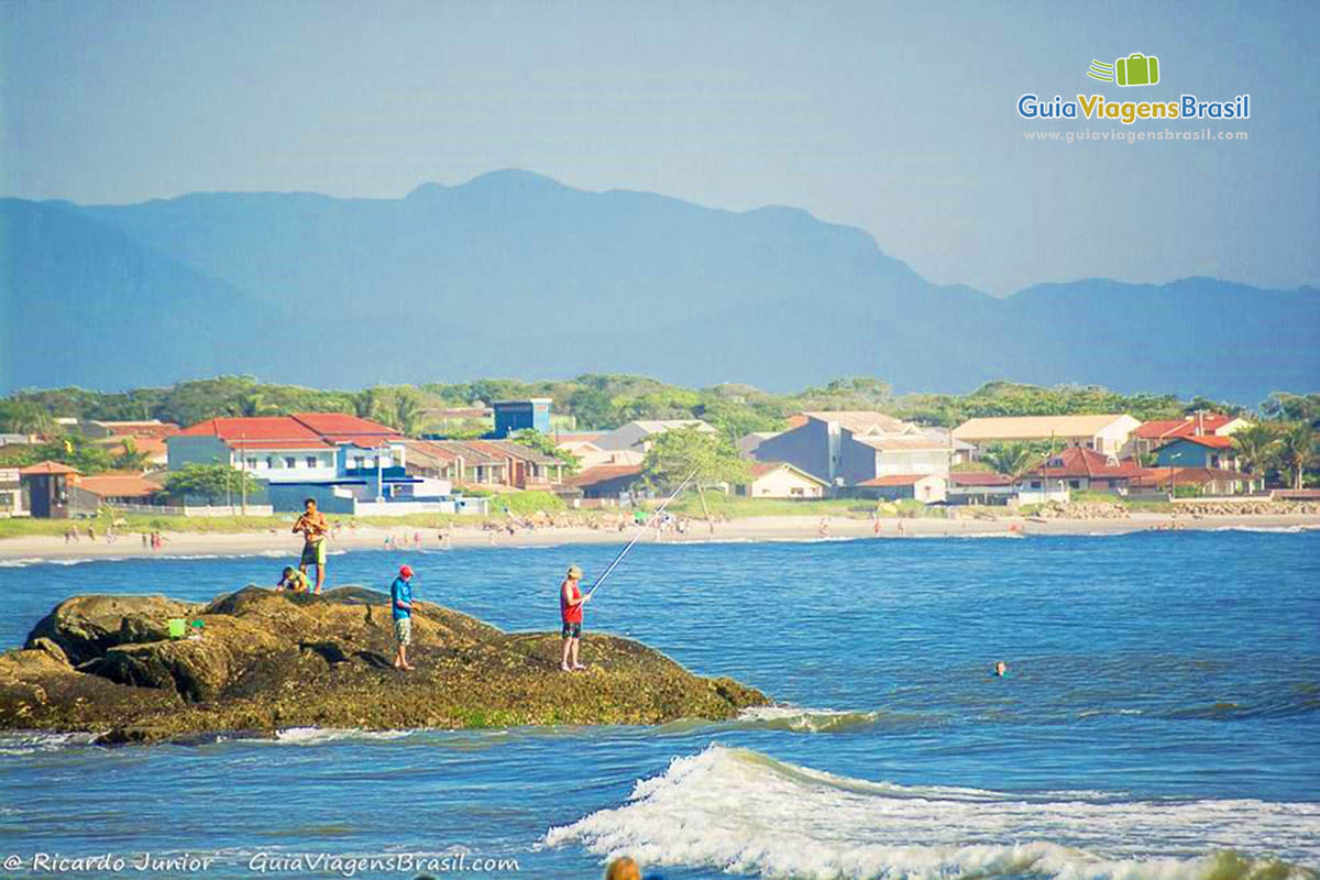 Imagem de homens pescando na Praia da Barra do Sai, em Itapoá, Santa Catarina, Brasil.