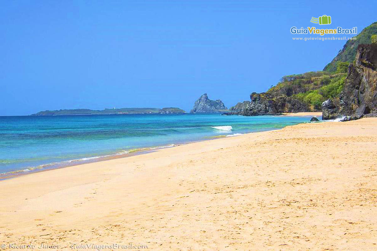 Imagem da praia com areia clara e águas transparentes da Praia da Cacimba do Padre, em Fernando de Noronha, Pernambuco, Brasil.