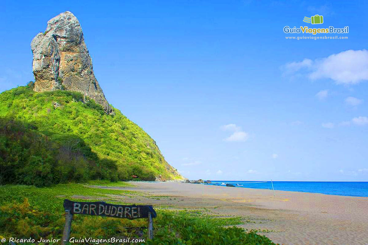 Imagem do canto da praia com uma linda vegetação no morro, na Praia da Conceição, em Fernando de Noronha, Pernambuco, Brasil.