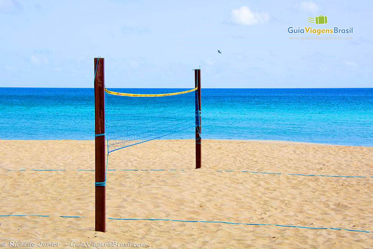 Imagem de uma rede de vôlei colocada e ao fundo mar na cor azul turquesa indescritível, na Praia da Conceição, em Fernando de Noronha, Pernambuco, Brasil.