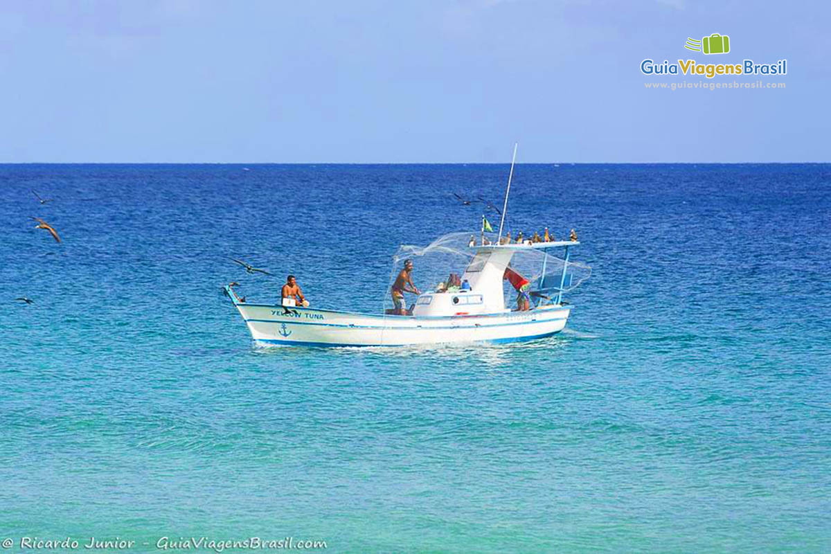 Imagem de barco de pescador em alto mar, completando mais um dia de pesca, na Praia da Conceição, em Fernando de Noronha, Pernambuco, Brasil.