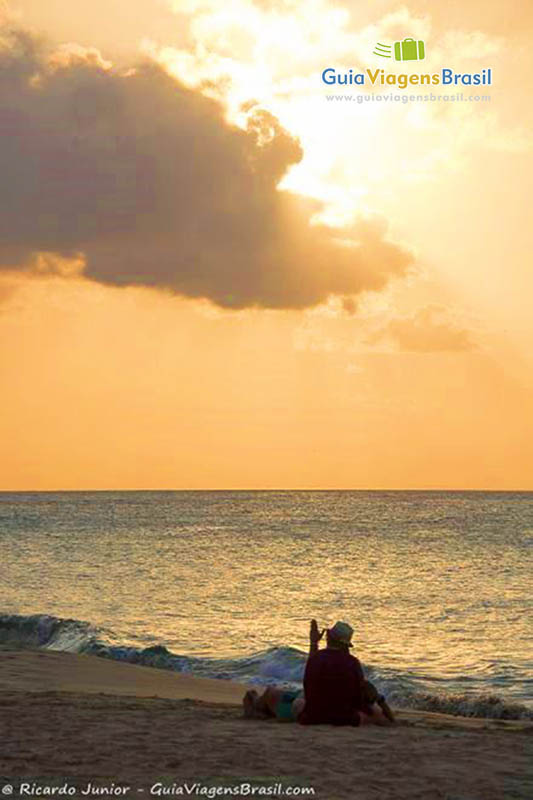 Imagem de turista curtindo um lindo pôr do sol, na Praia da Conceição, em Fernando de Noronha, Pernambuco, Brasil.